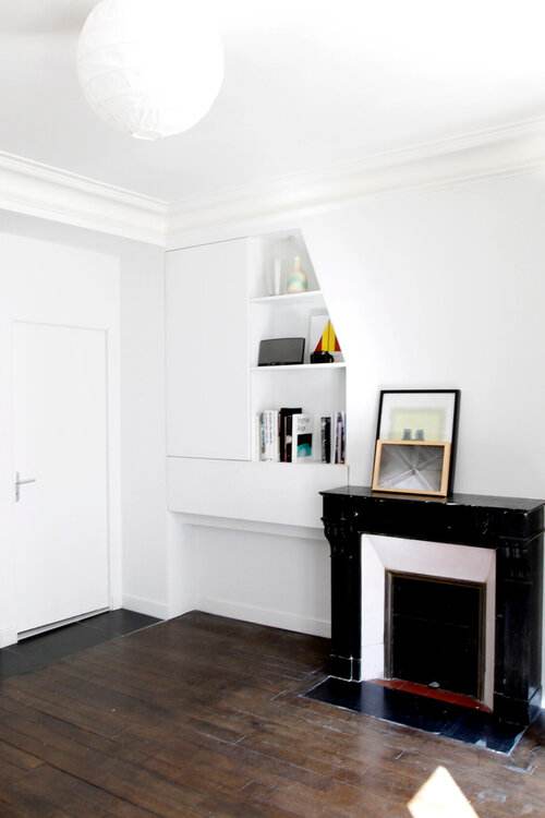 Appartement Oasis à Paris, séjour rénové, cheminée en marbre noir et rangements dessinés