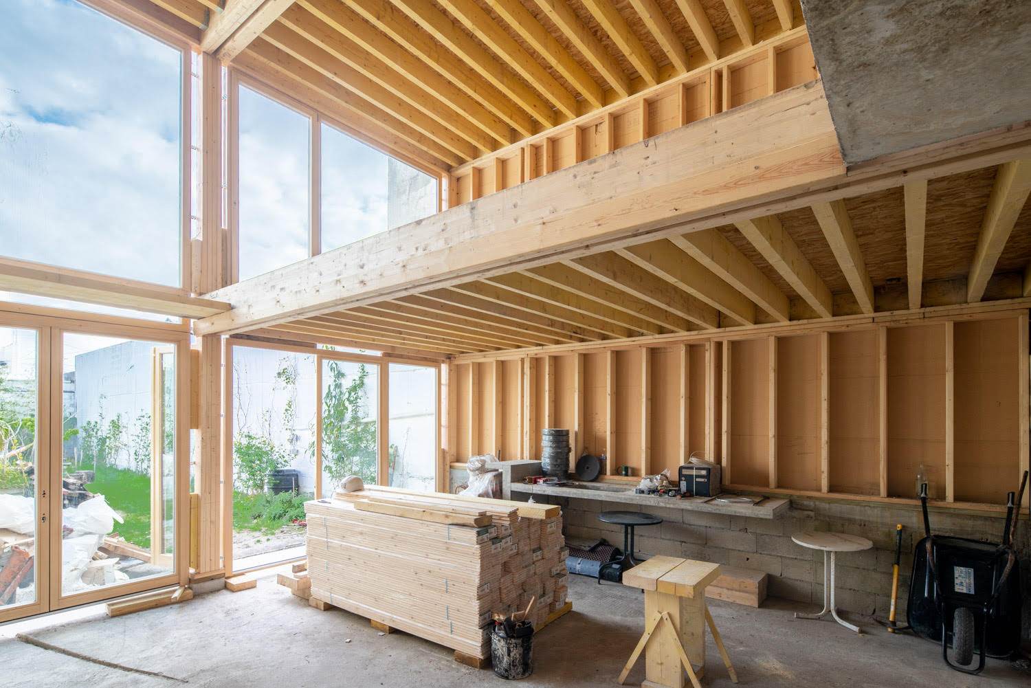 Volume intérieur sous charpente bois, baies ouvertes sur le jardin, chantier de la maison bois béton à Aubervilliers