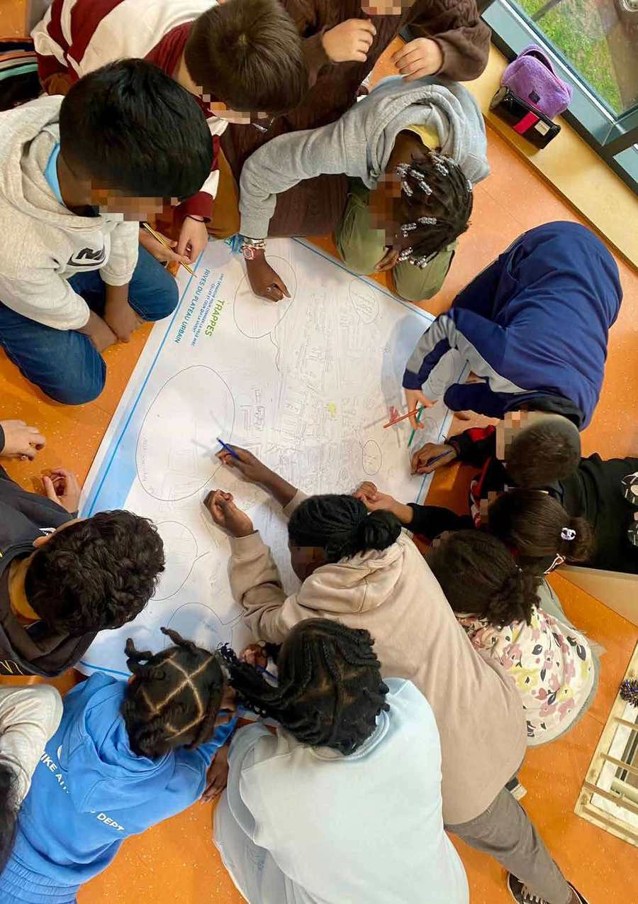 Enfants dessinant sur le plan du plateau urbain de Trappes